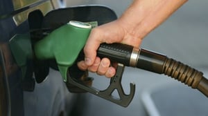 A gas pump nozzle is being used to fill a car with gas