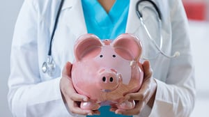 A doctor holds up a piggy bank