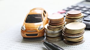 A small toy car sits next to several stacks of coins