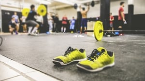 A pair of gym shoes sits on the floor of a very active gym