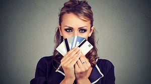 A woman is hiding her face with numerous credit cards