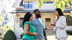 Couple talks with real estate agent in front of home