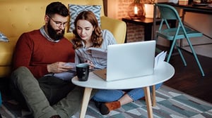 A couple sit in front of their laptop